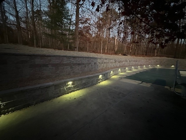 A twilight view of a brick wall hardscape demonstrating the garden lights installed